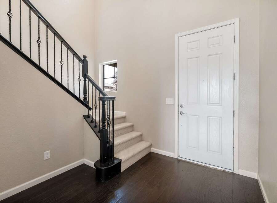 Step into this welcoming entryway featuring a grand staircase with elegant black wrought iron railings.
