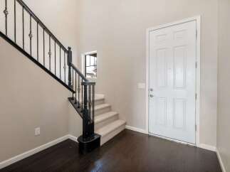 Step into this welcoming entryway featuring a grand staircase with elegant black wrought iron railings.