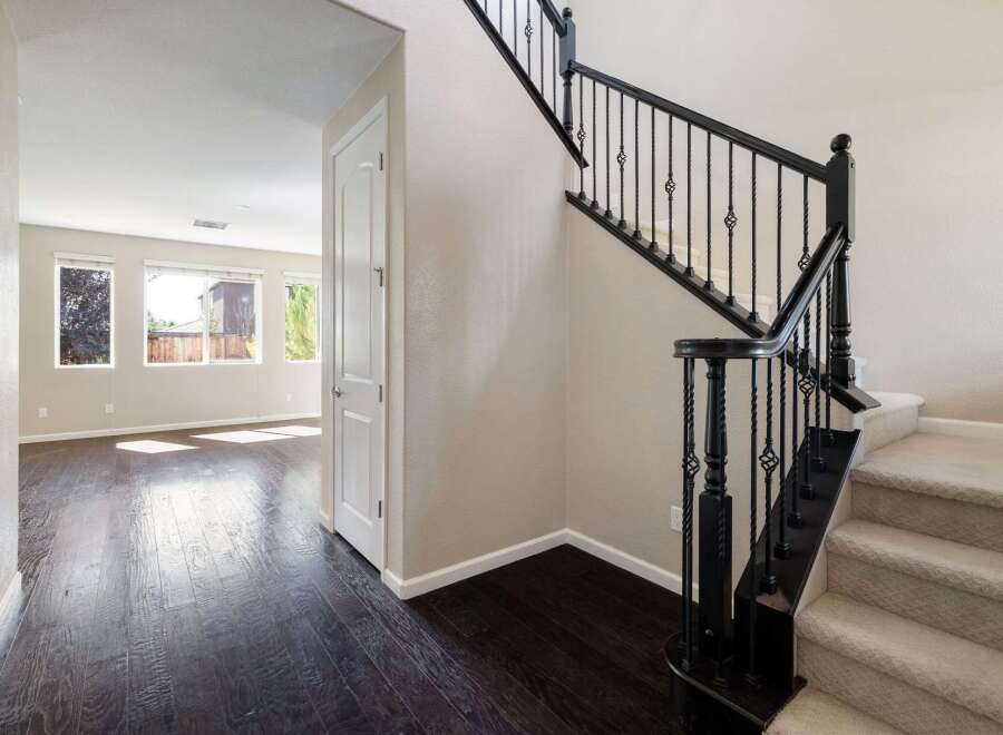 Step into this inviting home featuring a grand staircase with elegant black railings and plush carpeted steps.