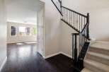 Step into this inviting home featuring a grand staircase with elegant black railings and plush carpeted steps.