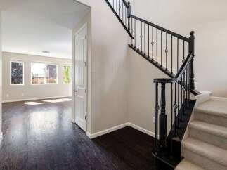 Step into this inviting home featuring a grand staircase with elegant black railings and plush carpeted steps.