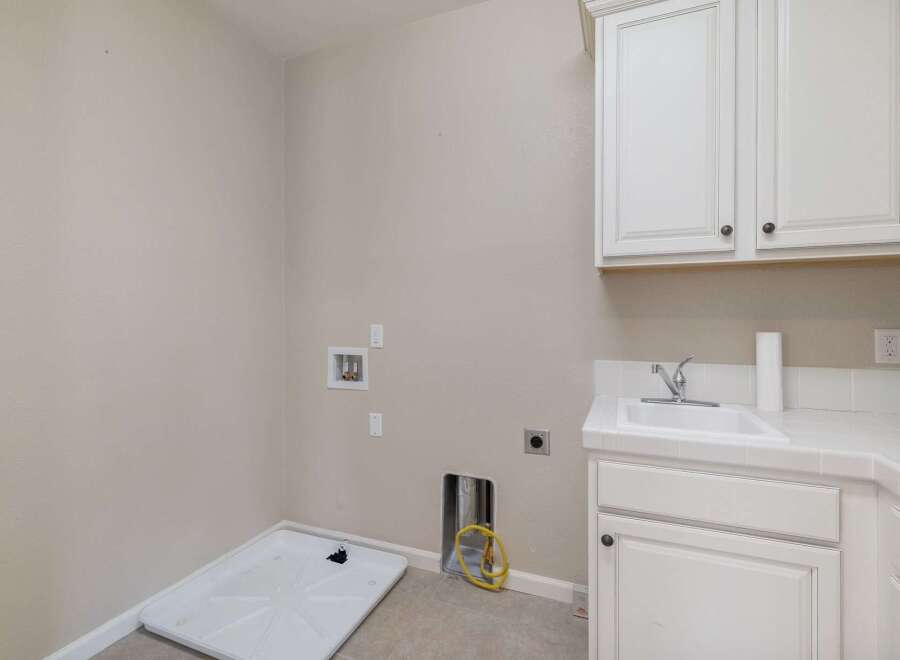 This laundry room features a utility sink and ample cabinet space for storage.