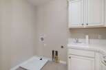 This laundry room features a utility sink and ample cabinet space for storage.