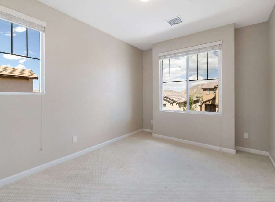 This bright and airy room features two large windows offering scenic views of the surrounding neighborhood and hills.