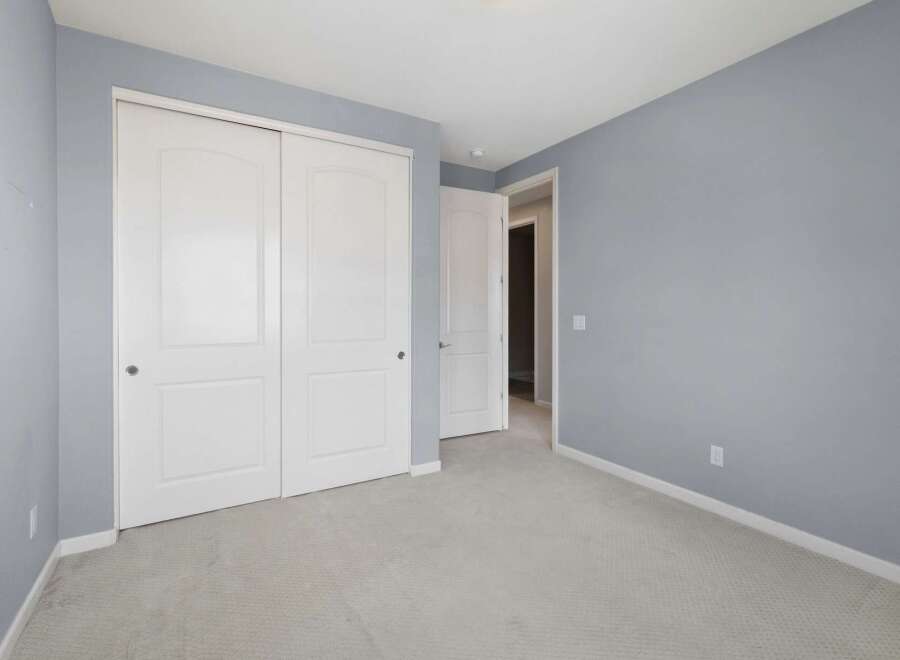 This bedroom features a spacious closet with double white doors, perfect for ample storage.