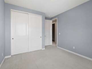 This bedroom features a spacious closet with double white doors, perfect for ample storage.