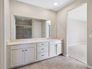 This spacious bathroom features a double vanity with ample counter space and storage, perfect for any household.