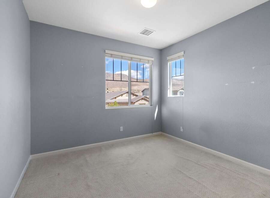 This unfurnished bedroom features light blue walls and a neutral carpet.