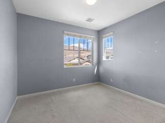 This unfurnished bedroom features light blue walls and a neutral carpet.