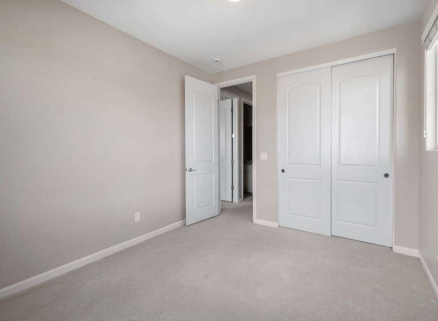 Discover comfort and convenience in this inviting bedroom, featuring a neutral color palette and plush carpeting for a serene atmosphere.