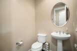This powder room features a sleek pedestal sink with modern chrome fixtures, complemented by an elegant oval mirror above.