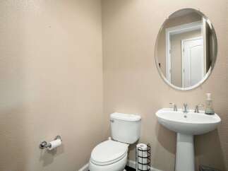 This powder room features a sleek pedestal sink with modern chrome fixtures, complemented by an elegant oval mirror above.