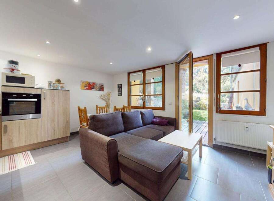 This charming living space seamlessly blends a modern kitchen with a comfortable living area, perfect for entertaining.