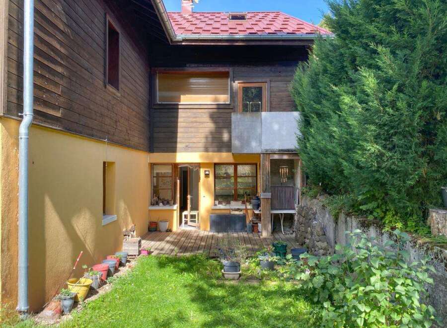 Discover this charming property featuring a rustic wooden exterior and a vibrant yellow-painted lower level.