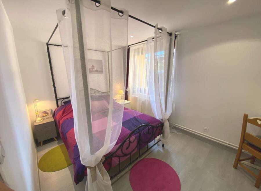 Discover this charming bedroom featuring a stylish four-poster bed adorned with a vibrant, geometric-patterned duvet.