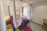 Discover this charming bedroom featuring a stylish four-poster bed adorned with a vibrant, geometric-patterned duvet.
