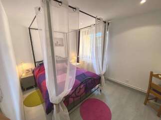 Discover this charming bedroom featuring a stylish four-poster bed adorned with a vibrant, geometric-patterned duvet.