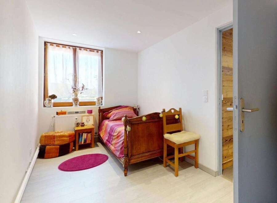This charming bedroom features a cozy wooden bed with colorful bedding, perfect for a restful night's sleep.