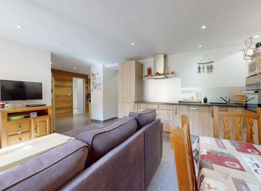 This open-concept living and dining area features a modern kitchen with ample cabinet space and a sleek range hood.