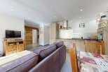 This open-concept living and dining area features a modern kitchen with ample cabinet space and a sleek range hood.