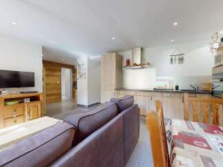 This open-concept living and dining area features a modern kitchen with ample cabinet space and a sleek range hood.