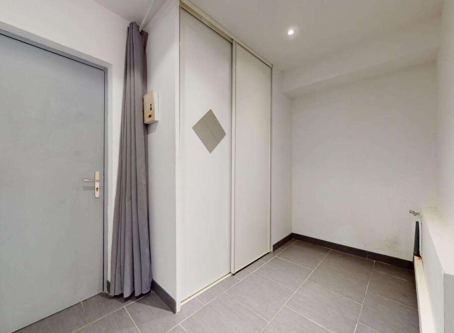 Discover this spacious entryway featuring a sleek gray door and convenient built-in closet space.