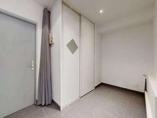 Discover this spacious entryway featuring a sleek gray door and convenient built-in closet space.