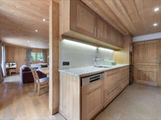Experience rustic charm in this beautifully appointed kitchen and living area, featuring warm wood paneling throughout.