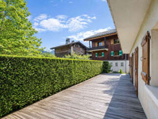 Enjoy the serene ambiance of this property, featuring a beautifully manicured hedge and a spacious wooden deck perfect for outdoor relaxation.