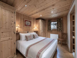 Experience rustic charm in this cozy bedroom, featuring warm wooden paneling throughout the walls and ceiling.