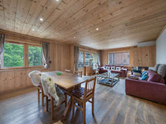 Experience cozy living in this charming wooden chalet, featuring a spacious dining area with a rustic wooden table perfect for family meals.