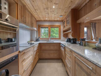 Experience rustic charm in this beautifully appointed wooden kitchen, featuring sleek granite countertops and ample cabinetry.