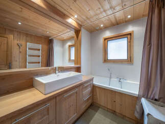 This charming bathroom features a spacious wooden vanity with a modern rectangular sink, complemented by a sleek chrome faucet.