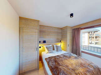 Experience cozy mountain living in this charming bedroom featuring a plush fur throw on the bed and warm wood paneling throughout.