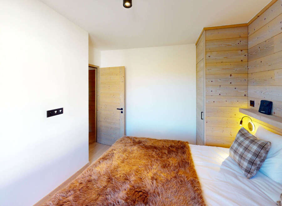 Experience cozy mountain living in this charming bedroom, featuring a plush, rustic fur throw blanket and a comfortable bed adorned with plaid accent pillows.