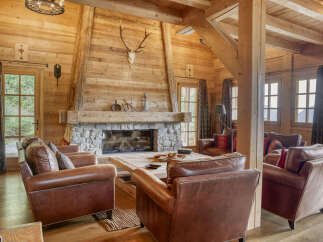 Experience rustic luxury in this stunning log cabin living room, featuring a grand stone fireplace as the centerpiece.