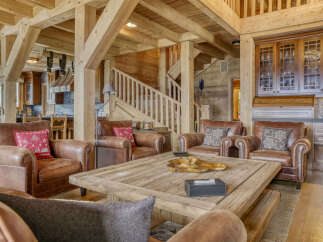 Experience rustic luxury in this stunning living room, featuring plush leather armchairs arranged around a substantial wooden coffee table.