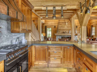 Experience rustic luxury in this stunning mountain kitchen, featuring a professional-grade gas range and a striking copper range hood.