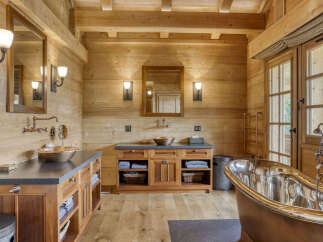 Experience rustic luxury in this stunning wooden bathroom, featuring a freestanding copper bathtub and a double vanity with vessel sinks.