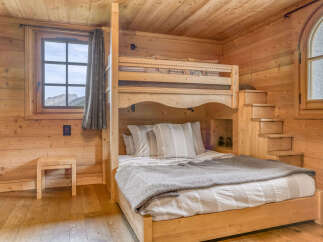 Experience cozy living in this charming wooden cabin bedroom, featuring a space-saving bunk bed with a comfortable lower double bed and a twin upper bunk.