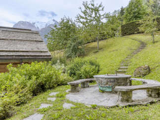 Experience the charm of this alpine retreat, featuring a rustic stone fire pit area with wooden benches perfect for gathering.