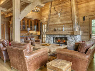 Experience rustic luxury in this stunning mountain lodge living room, featuring a grand stone fireplace and warm wood paneling.