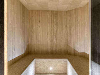 Experience ultimate relaxation in this luxurious steam room, featuring elegant travertine tile walls and ceiling.