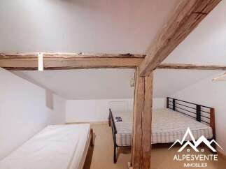 Discover this charming attic bedroom featuring exposed wooden beams and a rustic aesthetic.