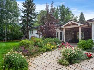 Welcome to this charming home featuring a beautifully landscaped garden with a variety of colorful flowers and lush greenery.