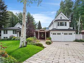 Discover this charming white home featuring a classic architectural style with a metal roof and a welcoming stone-accented entryway.