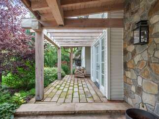 Experience seamless indoor-outdoor living with this charming covered patio, featuring a rustic wooden pergola and a stone accent wall.