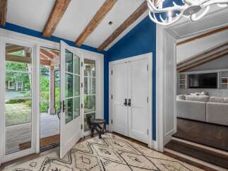 Step into this inviting entryway featuring striking blue walls and rustic exposed wooden beams on the vaulted ceiling.
