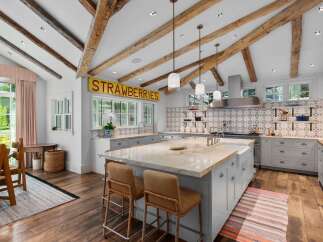 This stunning farmhouse kitchen boasts rustic charm with exposed wooden beams and a charming 'STRAWBERRIES' sign.