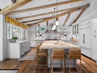 Experience rustic charm in this stunning kitchen, featuring exposed wooden beams and a unique 'Strawberries' sign.